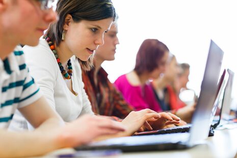 Schülerin und Schüler  an einem Laptop.