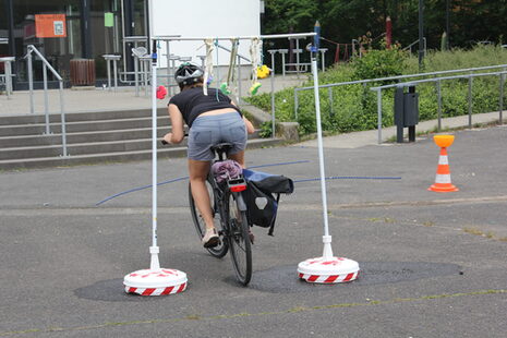Una donna passa in bicicletta sotto un ostacolo.